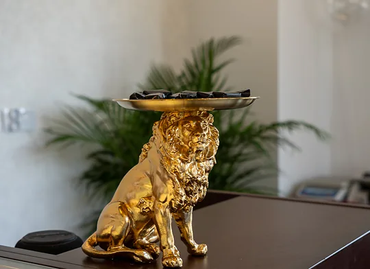 Złota figurka lwa z mosiężną tacą stojąca na ladzie salonu Goldmania